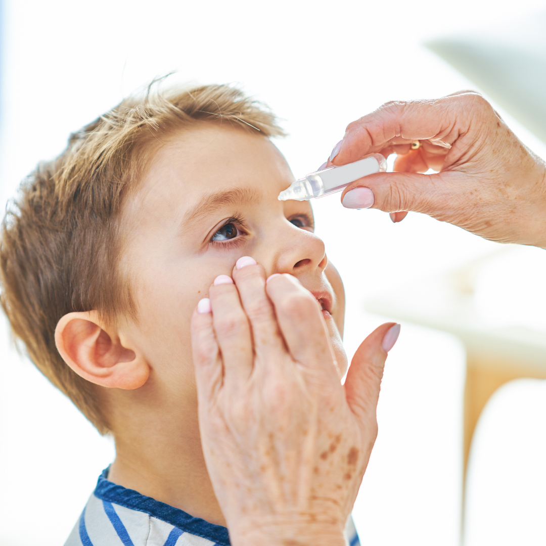 Child has eye drops administered into his eye. 