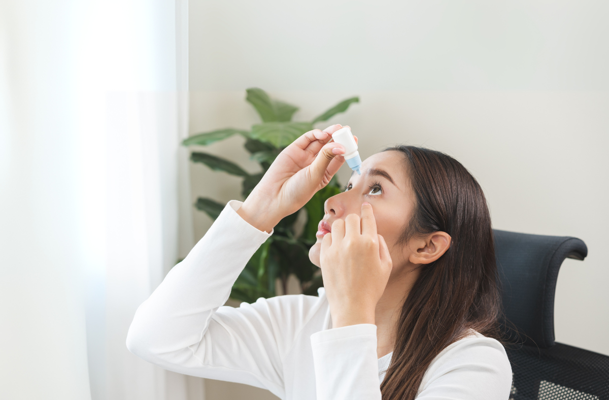 Woman tilts head backwards to administer eye drops