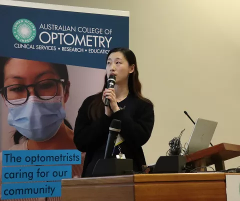 Female early career optometrist speaks at a podium