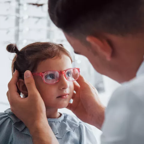 Young girl tries new pink glasses