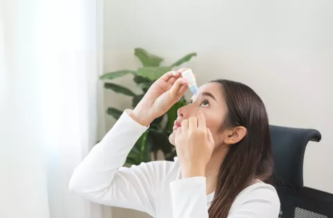 Woman tilts head backwards to administer eye drops